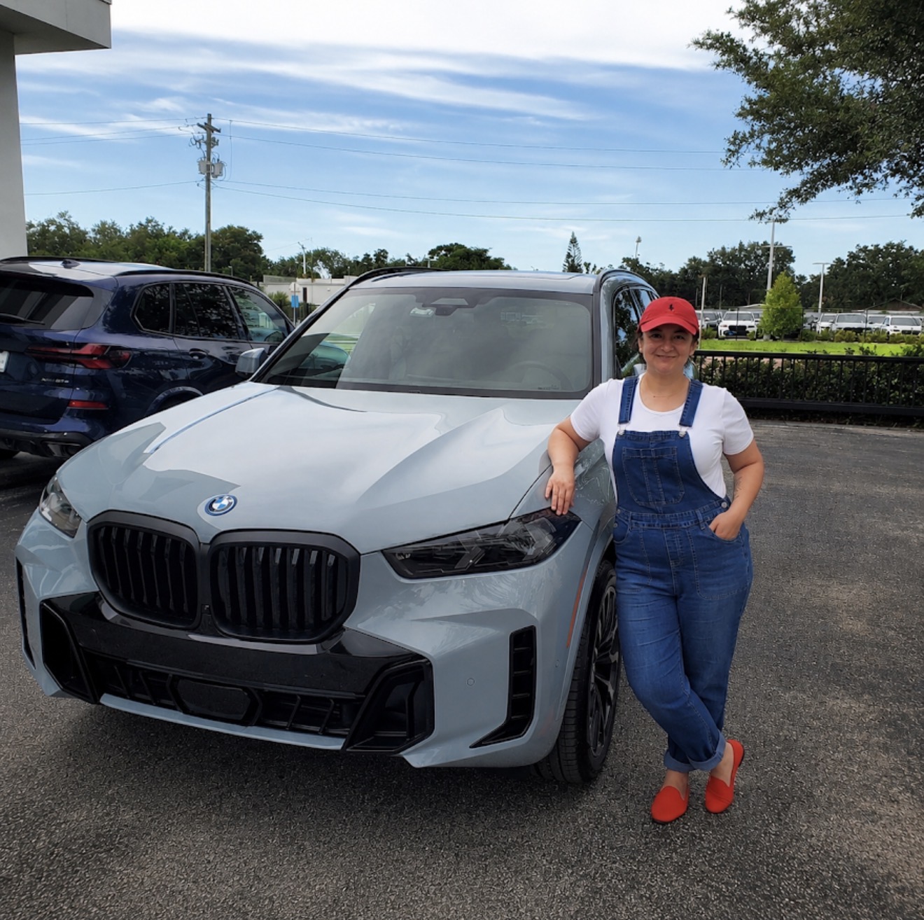 Deal Drvn client with her new BMW X5 50e at the dealership — a real result from Deal Drvn's flat-fee car buying service