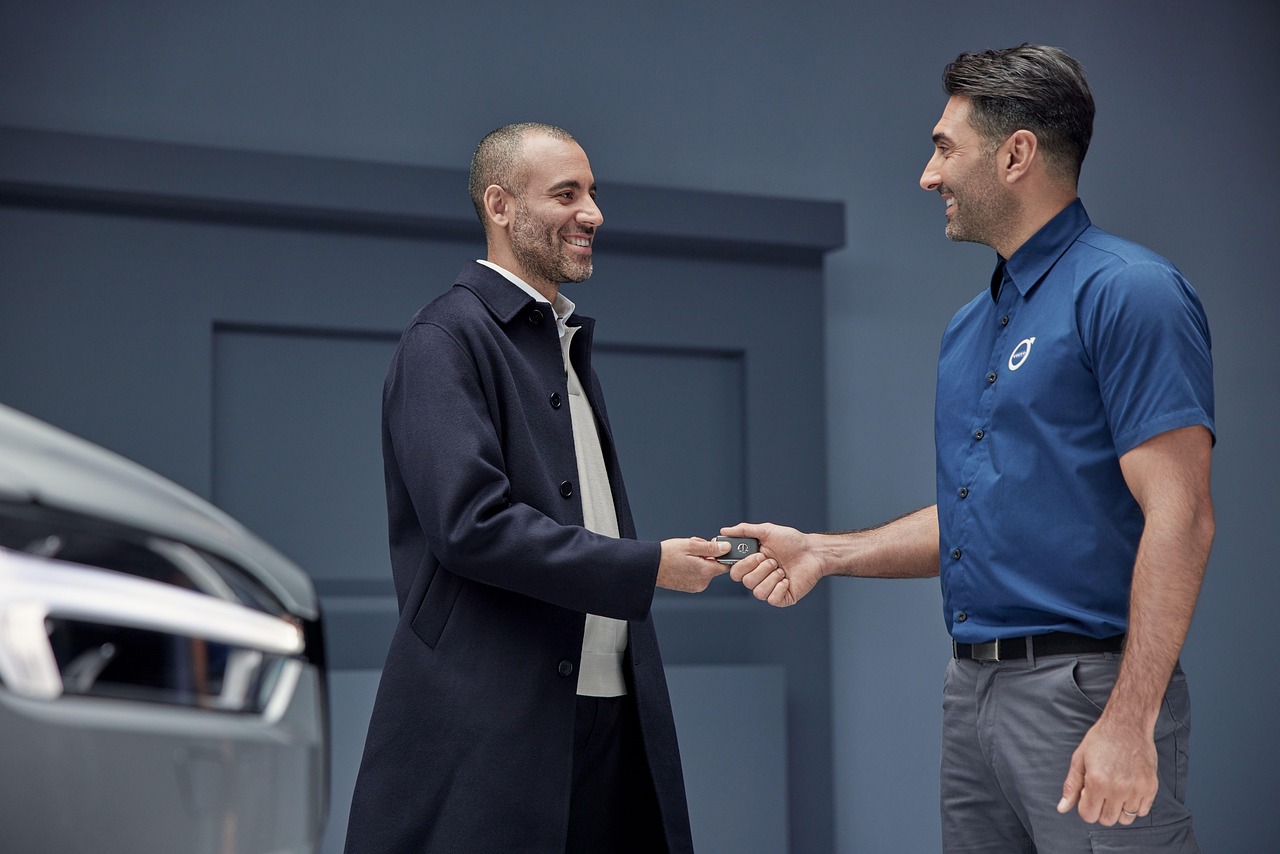 Car dealership salesperson handing keys to a buyer after a successful negotiation